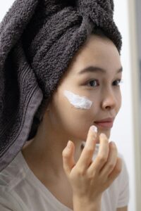 Close-up of a woman applying face cream, emphasizing skincare routine and self-care habits.